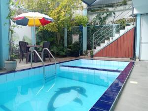 a swimming pool with a table and an umbrella at GT Homes Peradeniya in Peradeniya