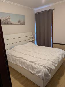 a white bed in a bedroom with a window at 4-persoons appartement met een mooi uitzicht in De Panne