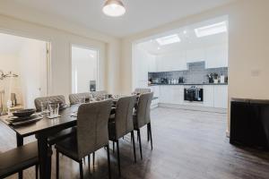a dining room with a table and chairs and a kitchen at Large 5BR 3BA Home Leamington Spa Driveway Parking WI-FI in Leamington Spa