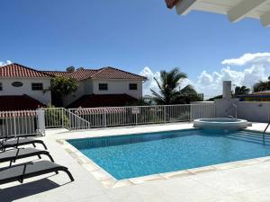 a swimming pool with two chairs and a house at This is a beachfront 3 bedroom, 3 bathroom villa, family-friendly activities in Christ Church