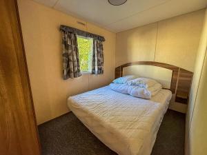 um pequeno quarto com uma cama com lençóis brancos e uma janela em Lovely Caravan For Hire At Manor Park In Hunstanton Ref 23053B em Hunstanton
