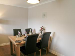 a dining room with a wooden table and black chairs at Kerrera View in Oban