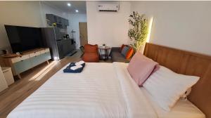 een slaapkamer met een groot wit bed en een woonkamer bij Sport villa Huahin, Room 225, Studio Queen Bed pool view and Kitchenette, 2nd Floor in Hua Hin