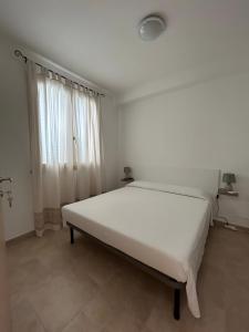 a white bed in a room with a window at L'angolo Porto Torres in Porto Torres +12 photos