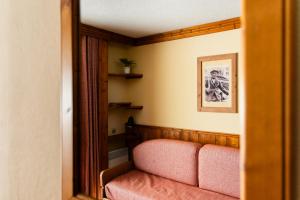 a living room with a pink couch and a mirror at Le Cheval Blanc - Village Montana in Val Thorens