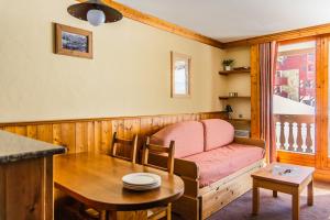 a living room with a pink couch and a table at Le Cheval Blanc - Village Montana in Val Thorens