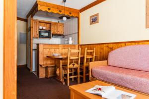 a room with a bed and a table and a kitchen at Le Cheval Blanc - Village Montana in Val Thorens