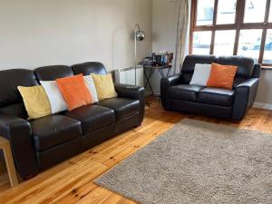 - un salon avec un canapé en cuir noir et des oreillers colorés dans l'établissement Holiday Home Achill Sound Holiday Village No 11 by Interhome, à Achill Sound