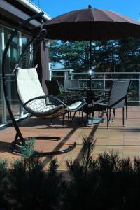 um alpendre com cadeiras e um guarda-sol num pátio em Holiday Terrace Nida em Nida