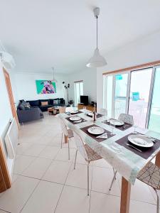Una sala de estar con una mesa con sillas y una sala de estar en Os Dias Felizes, en Tavira