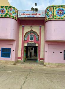 AyodhyaにあるOmji Darshan Bhawan - 2km from Ram Templeの通りにある2つのガレージドアがあるピンク色の建物 +3枚の写真