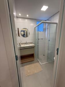 a bathroom with a glass shower and a sink at Momentos únicos em Foz te esperam in Foz do Iguaçu