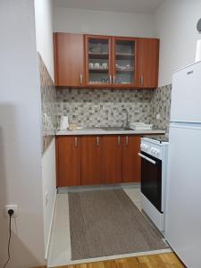 a kitchen with wooden cabinets and a white refrigerator at Apartment Čapljina in Čapljina