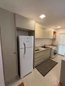 a kitchen with a white refrigerator and a sink at Momentos únicos em Foz te esperam in Foz do Iguaçu