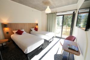 a hotel room with two beds and a window at Le Rocher Du Cerf in Le Lioran