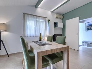 une salle à manger avec une table en bois et des chaises vertes dans l'établissement Holiday Home Tonka by Interhome, à Rabac