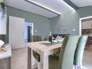 une salle à manger avec une table en bois et des chaises vertes dans l'établissement Holiday Home Tonka by Interhome, à Rabac