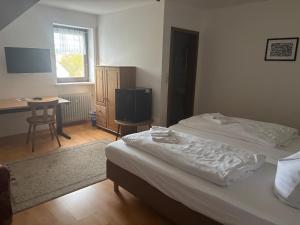 a bedroom with a bed and a desk and a television at Gasthof Schrätzenstaller in Hettenshausen