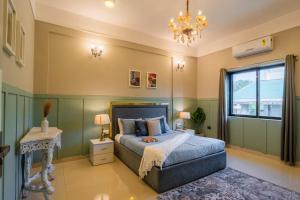 a bedroom with a bed and a chandelier at EKO STAY Gold - Gatsby Villa in Lonavala +23 photos