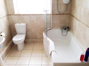 a bathroom with a white tub and a toilet at Jug And Glass Cottage in Upper Langwith