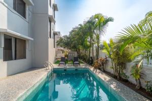 a swimming pool in front of a house with palm trees at EKO STAY Gold - Gatsby Villa in Lonavala