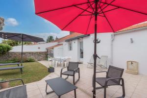 ein roter Sonnenschirm auf einer Terrasse mit Stühlen und einem Tisch in der Unterkunft La Birochère - 400 m plage - Parking in Pornic