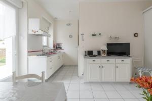 eine weiße Küche mit weißen Schränken und einem Tisch in der Unterkunft La Birochère - 400 m plage - Parking in Pornic + 4 Fotos