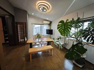 Zimmer mit einem Tisch, einer Bank und Pflanzen in der Unterkunft ZYZ Higashijūjō House in Wada