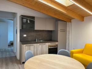 a kitchen with a table and a yellow chair at Residence La Corte in Vezza dʼOglio