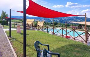 Un dosel rojo sobre un banco junto a una piscina en 2 Bedroom Nice Home In Porchiano, en Porchiano