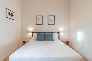 a bedroom with a large white bed with blue pillows at Hotiday Apartments Siracusa in Syracuse