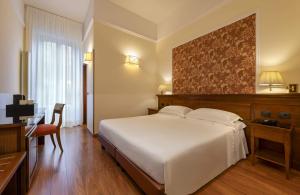Un dormitorio con una gran cama blanca y un escritorio. en Lancaster Hotel, en Milán 50 fotos más