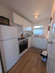 a kitchen with white cabinets and a white refrigerator at Chalet 145, Hemsby - Two bed chalet, sleeps 5, pet friendly, bed linen and towels included and close to beach! in Great Yarmouth