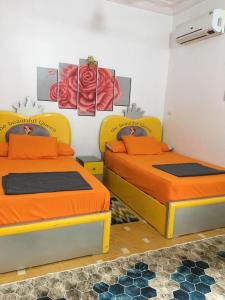 two beds in a room with orange sheets at Gana kato in Aswan