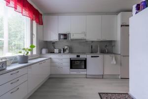 a white kitchen with white cabinets and appliances at Rovaniemi Spacious Lapland Vacation Home with Private Sauna & Lappish Fire Hut in Rovaniemi