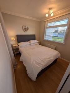a bedroom with a large bed and a window at Chalet 145, Hemsby - Two bed chalet, sleeps 5, pet friendly, bed linen and towels included and close to beach! in Great Yarmouth