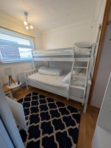 a bedroom with two bunk beds and a rug at Chalet 145, Hemsby - Two bed chalet, sleeps 5, pet friendly, bed linen and towels included and close to beach! in Great Yarmouth