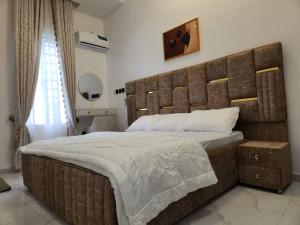 Un dormitorio con una cama grande con un cabecero grande de madera. en LPMD Apartment, en Ikuata