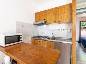eine Küche mit einer Mikrowelle und einer hölzernen Arbeitsplatte in der Unterkunft Holiday Home Villa 12 by Interhome in SantʼAmanza