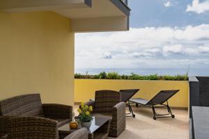 eine Terrasse mit Stühlen, einem Tisch und einer gelben Wand in der Unterkunft Relax Garden House Tranquility & Comfort in Florenças