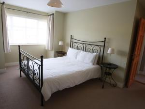 a bedroom with a bed with white sheets and a window at Holiday Home Glen Ard HH No 1 by Interhome in Dunmore East