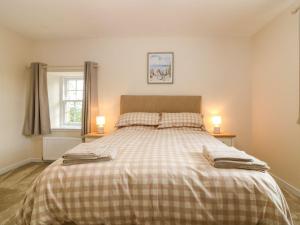 a bedroom with a bed with a plaid blanket at Bankhead Of Lour Cottage in Kingsmuir