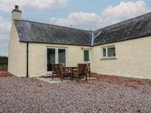 a table and chairs in front of a house at Bankhead Of Lour Cottage in Kingsmuir