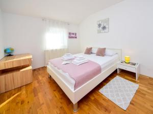 a bedroom with a white bed and a wooden floor at Holiday Home Marija by Interhome in Primorski Dolac