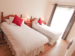 Cette chambre comprend 2 lits avec des oreillers blancs et rouges. dans l'établissement Holiday Home Kilkee HH - GF - TR1 Type C - No 903 by Interhome, à Kilkee