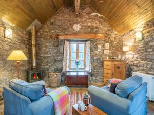 a living room with two blue couches and a stone wall at Holiday Home The Romantic Bothy by Interhome in Invermoriston