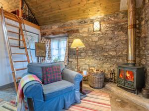 a living room with a ladder and a chair and a stove at Holiday Home The Romantic Bothy by Interhome in Invermoriston
