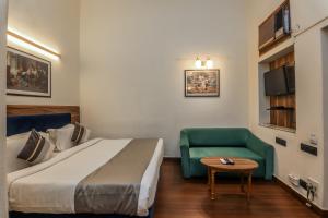 a hotel room with a bed and a green couch at asar CP Outer Circle by Orion Hotels in New Delhi