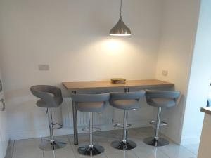 a kitchen with a wooden table with four bar stools at Holiday Home Behy Lodge Glenbeigh by Interhome in Behy Bridge