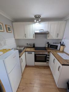 a kitchen with white cabinets and white appliances at 194, Belle Aire, Hemsby - Two bed recently renovated chalet, sleeps 4, pet friendly, free Wi-Fi and bed linen and towels included in Hemsby +13 photos